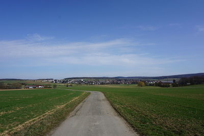 Road amidst agricultural field against sky