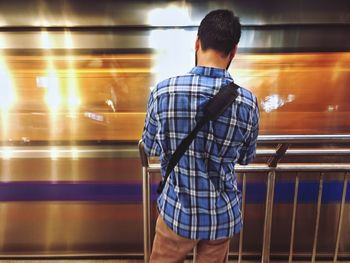 Rear view of man standing at railroad station