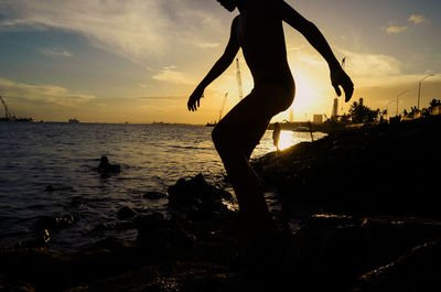 Silhouette people on beach against sky during sunset