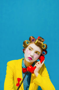 Portrait of young woman against blue background