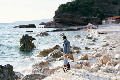 Rear view of man standing on rocks at beach