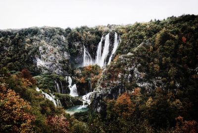 Scenic view of waterfall in forest against clear sky