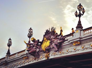 Low angle view of statues on building against sky