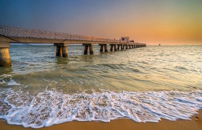 Pier over sea against sky during sunset