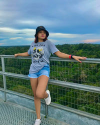 Portrait of smiling woman standing against railing