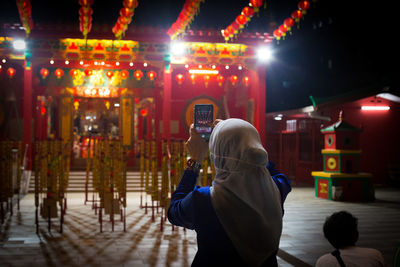 Rear view of woman photographing in temple