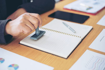 Midsection of man using mobile phone on table