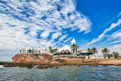 View of building by sea against cloudy sky