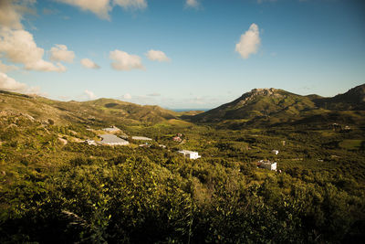 Scenic view of green mountains against sky on sunny day