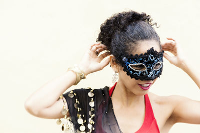 Portrait of a woman wearing venice carnival mask against light background. 