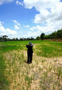 Man photographing on field against sky