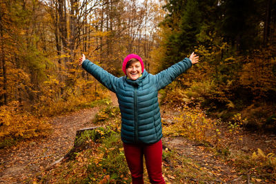 Full length of smiling young woman standing in forest