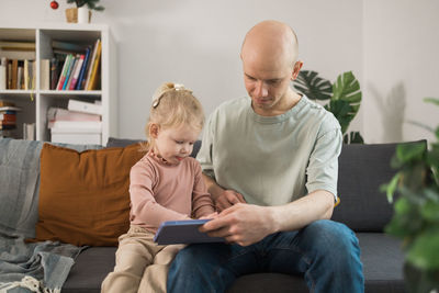 Mother and daughter sitting on sofa at home