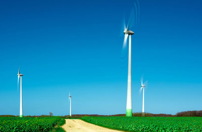 Low angle view of windmill against clear blue sky