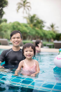 Portrait of happy girl with father in swimming pool