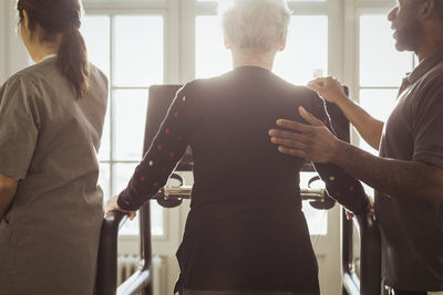 Male healthcare assisting senior woman exercising on treadmill in nursing home