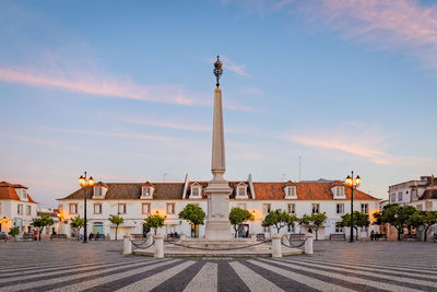 Statue in city against sky