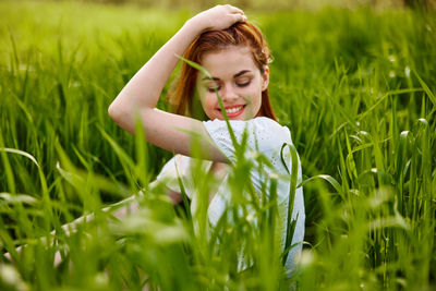 Portrait of young woman standing amidst plants on field