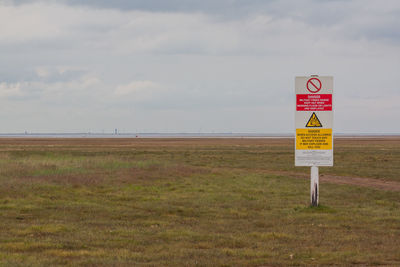 Road sign by sea against sky