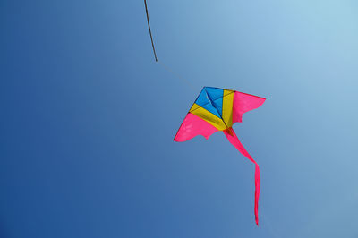 Low angle view of kite flying against clear blue sky