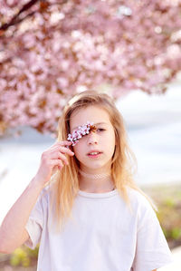 Portrait of young woman standing against trees