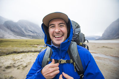 Portrait of happy backpacker with blue rain jacket on.