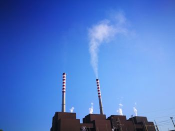 Low angle view of factory against blue sky