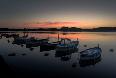 Boats moored in lake against sky during sunset