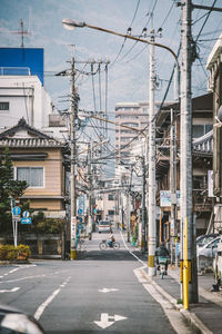 Road by buildings in city against sky