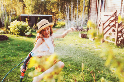 Smiling girl watering plants in garden