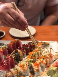 Midsection of person having sushi in restaurant