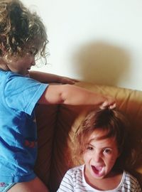Brother pulling sister hair on sofa at home