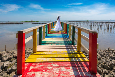 Side view of woman standing on pier over sea