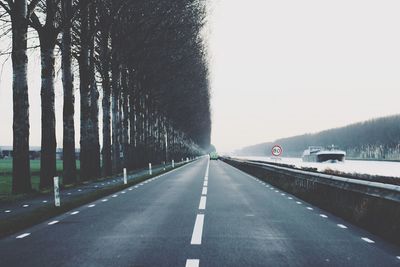 Road amidst trees against clear sky