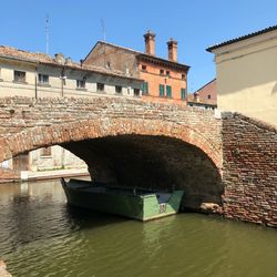 Arch bridge over river against buildings