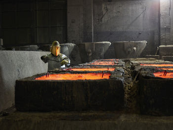 Industry, worker checking liquid copper in casting moulds with pliers