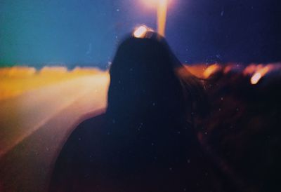 Close-up portrait of silhouette woman against illuminated window at night
