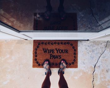 Low section of woman standing on doormat