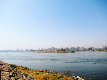 Scenic view of sea and buildings against clear sky