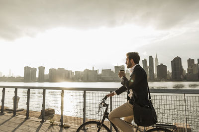 Usa, new york city, businessman on bicycle with takeaway coffee