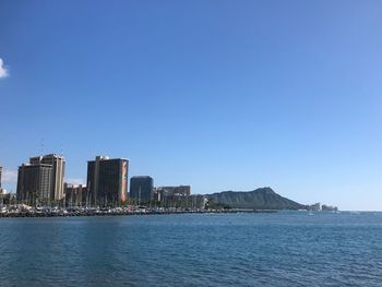 City at waterfront against blue sky