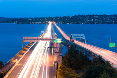 Light trails on bridge over city against sky