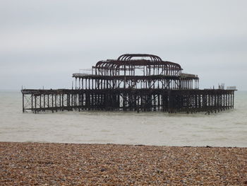 Old ruins of burnt brighton west pier in sea against sky