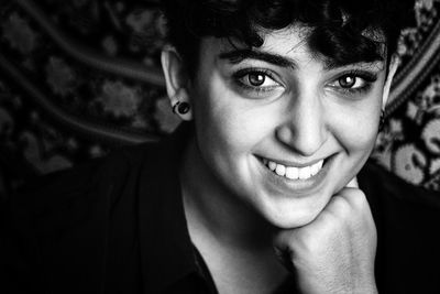 Close-up portrait of happy young woman with hand on chin