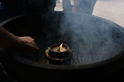 Cropped hand of person holding incense at temple