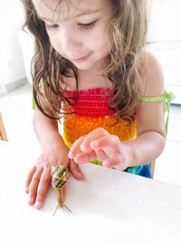 Girl playing with snail on table at home