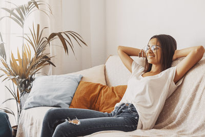 Young woman sitting on bed at home