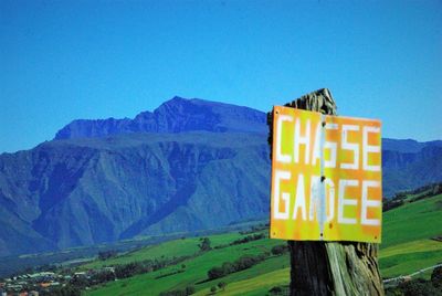 Information sign on mountain against clear blue sky