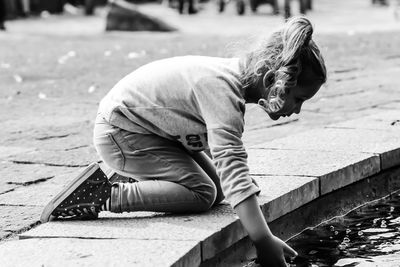 Girl dipping hand into pond