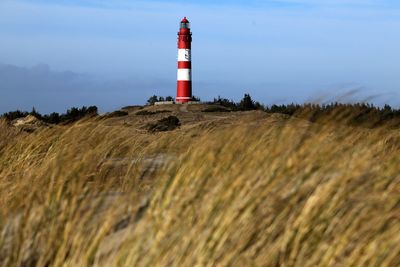 Lighthouse on landscape against sky